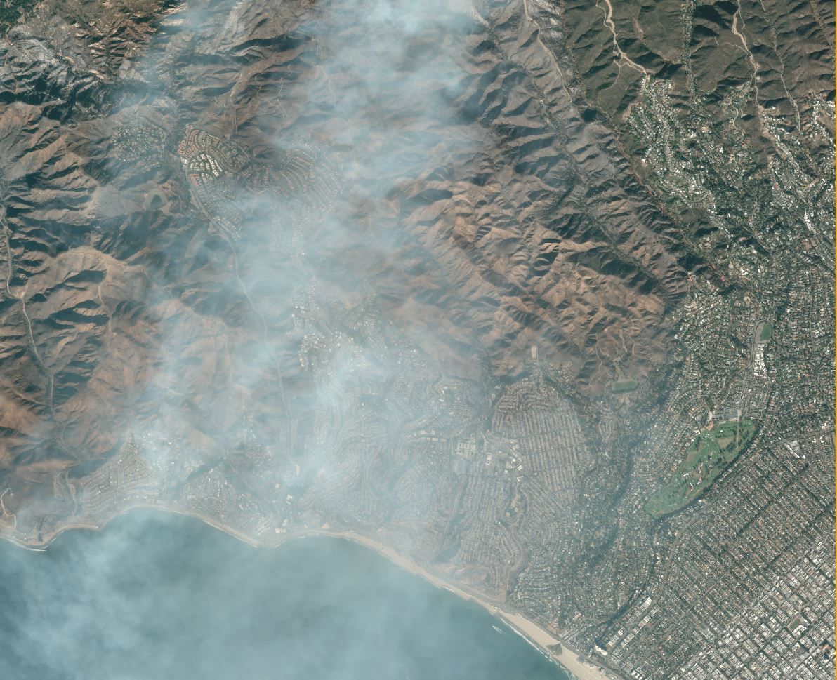 Satellite image showing a city area and a forest that has been ravaged by fire.